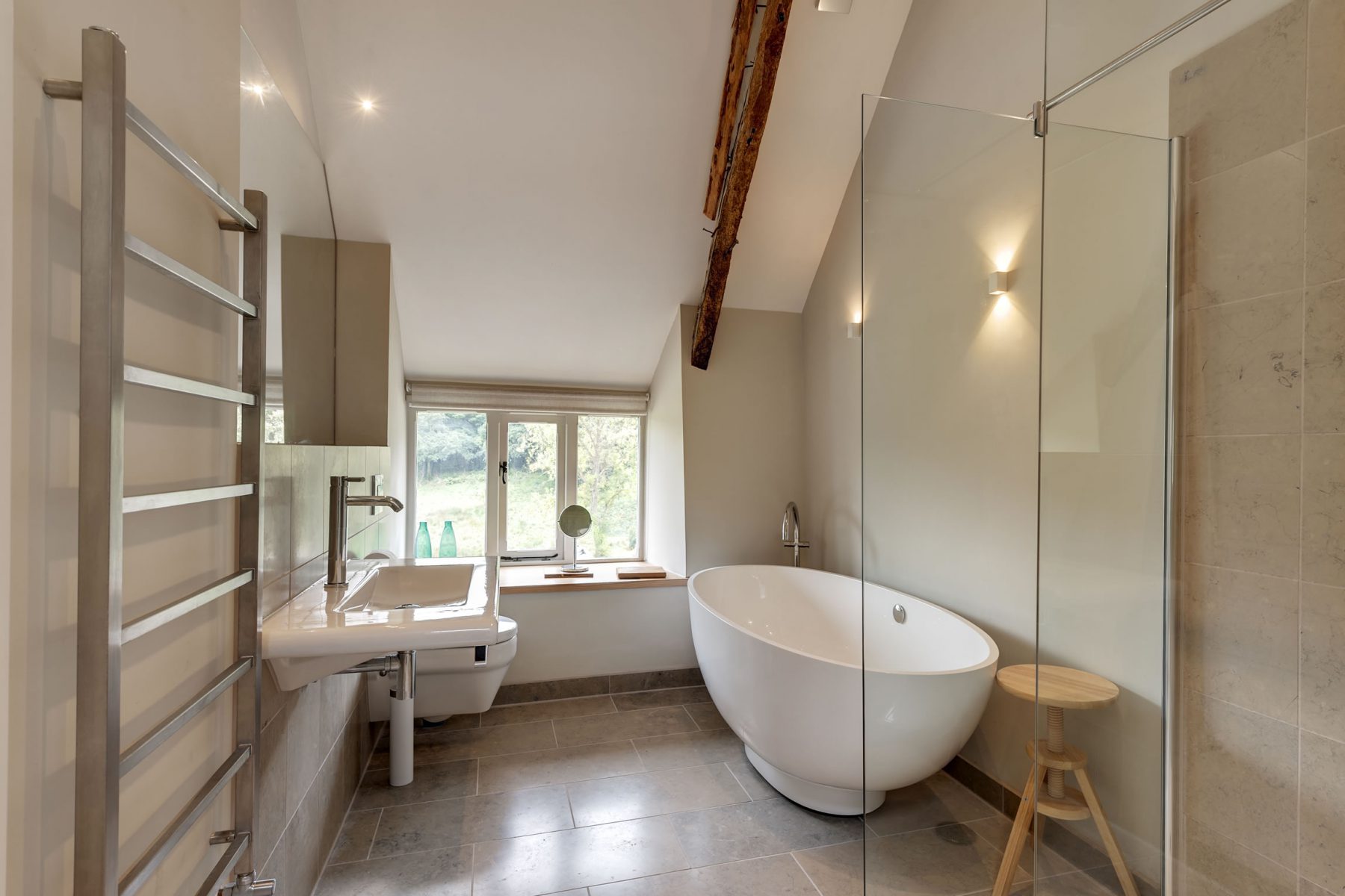 Duravit bathroom sanitary ware with wet room shower and contemporary free standing bath, all beneath original oak trusses of farmhouse roof.