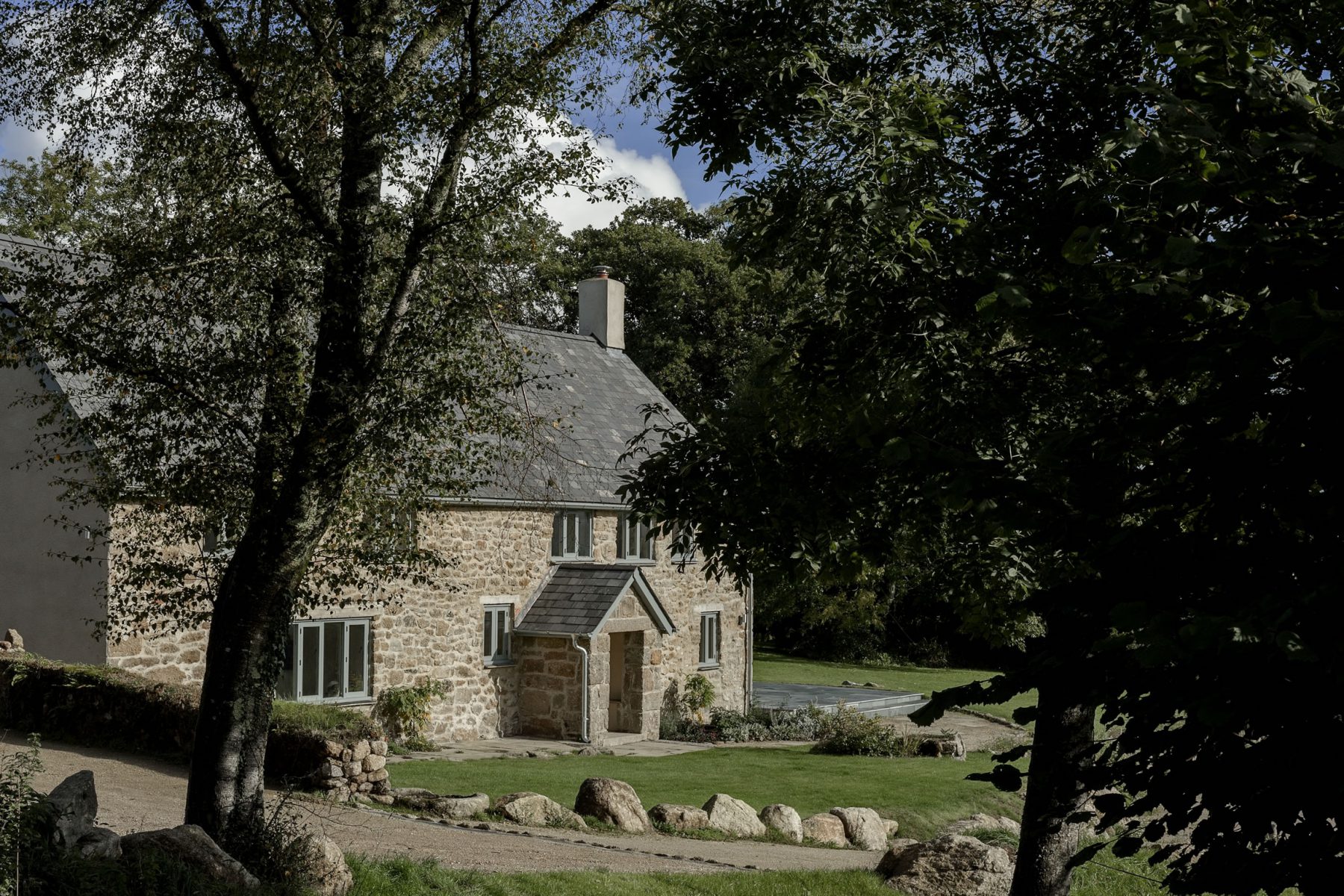 A traditional granite stone and slate roof farmhouse in Dartmoor, refurbished, renovated and extended with modern glass and flat roofed additions.