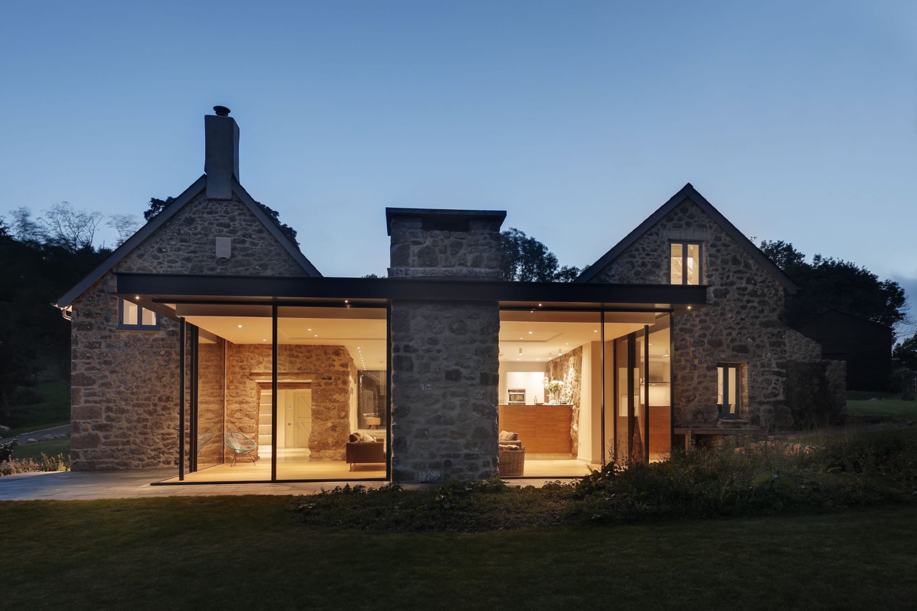 Glass box extension sandwiched between stone farmhouse and barn, with new stone chimney to compliment existing walls.