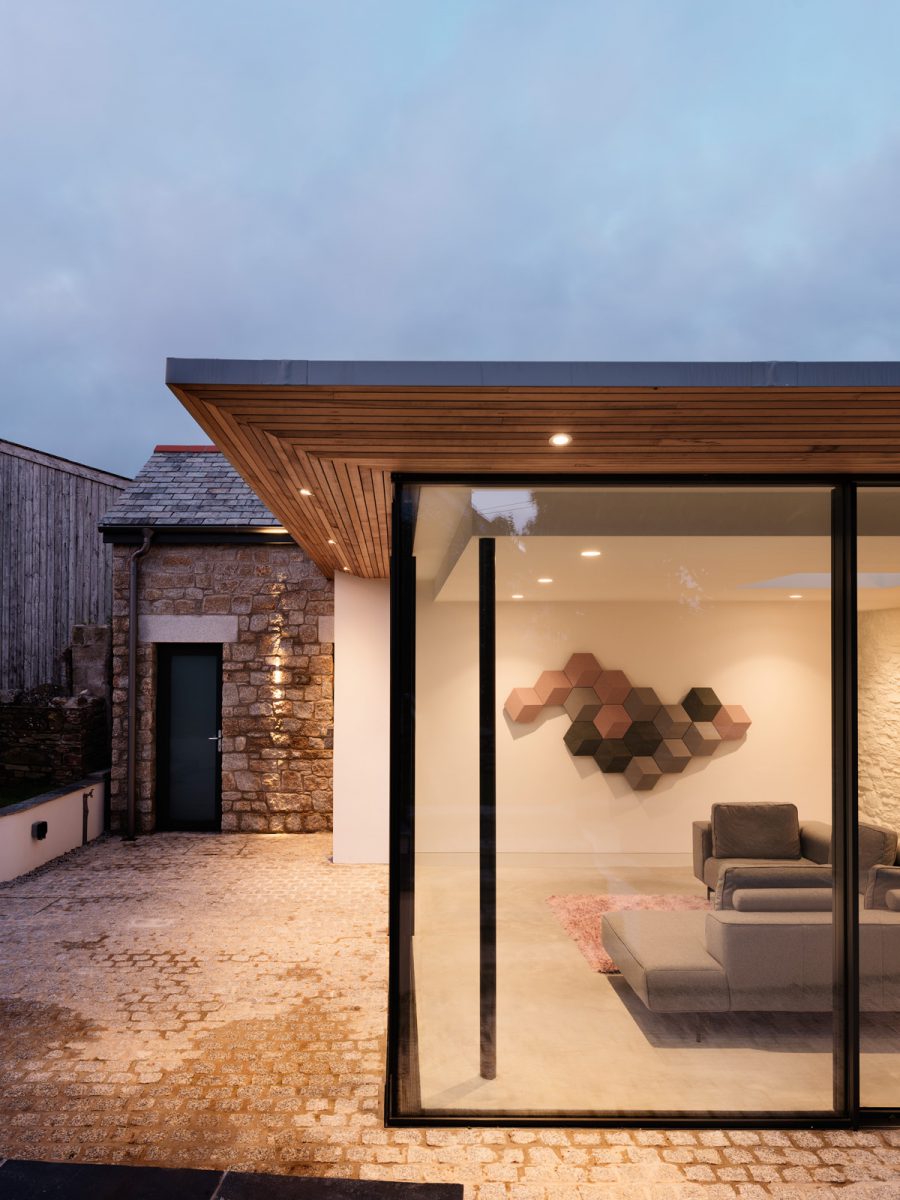 Floor to ceiling sliding glass doors. Glazed corner with elegant roof overhang finished in western red cedar cladding. Granite setts to external paving. Polished concrete floor internally.