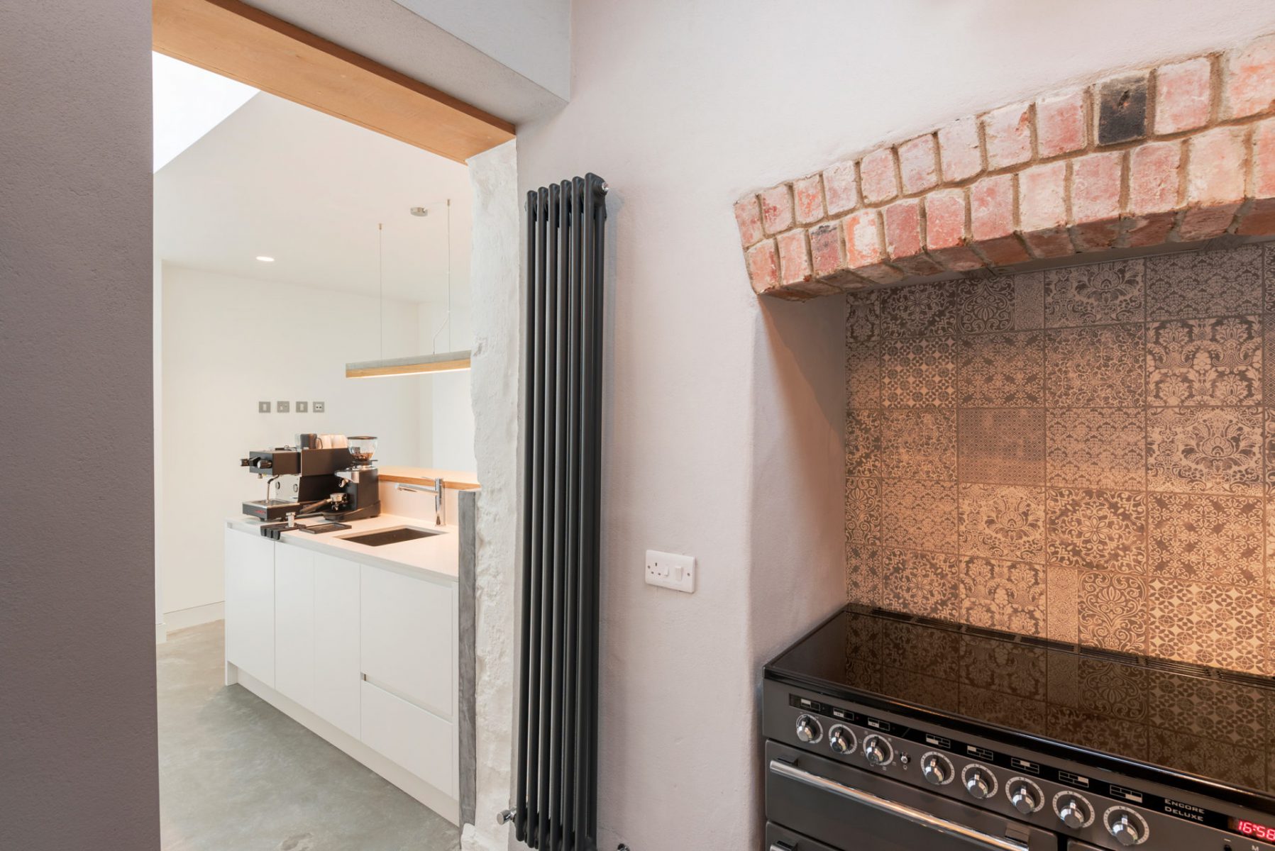 Range oven in original fire place with clay tiles and brick lintel. Contemporary coffee island joinery in background.