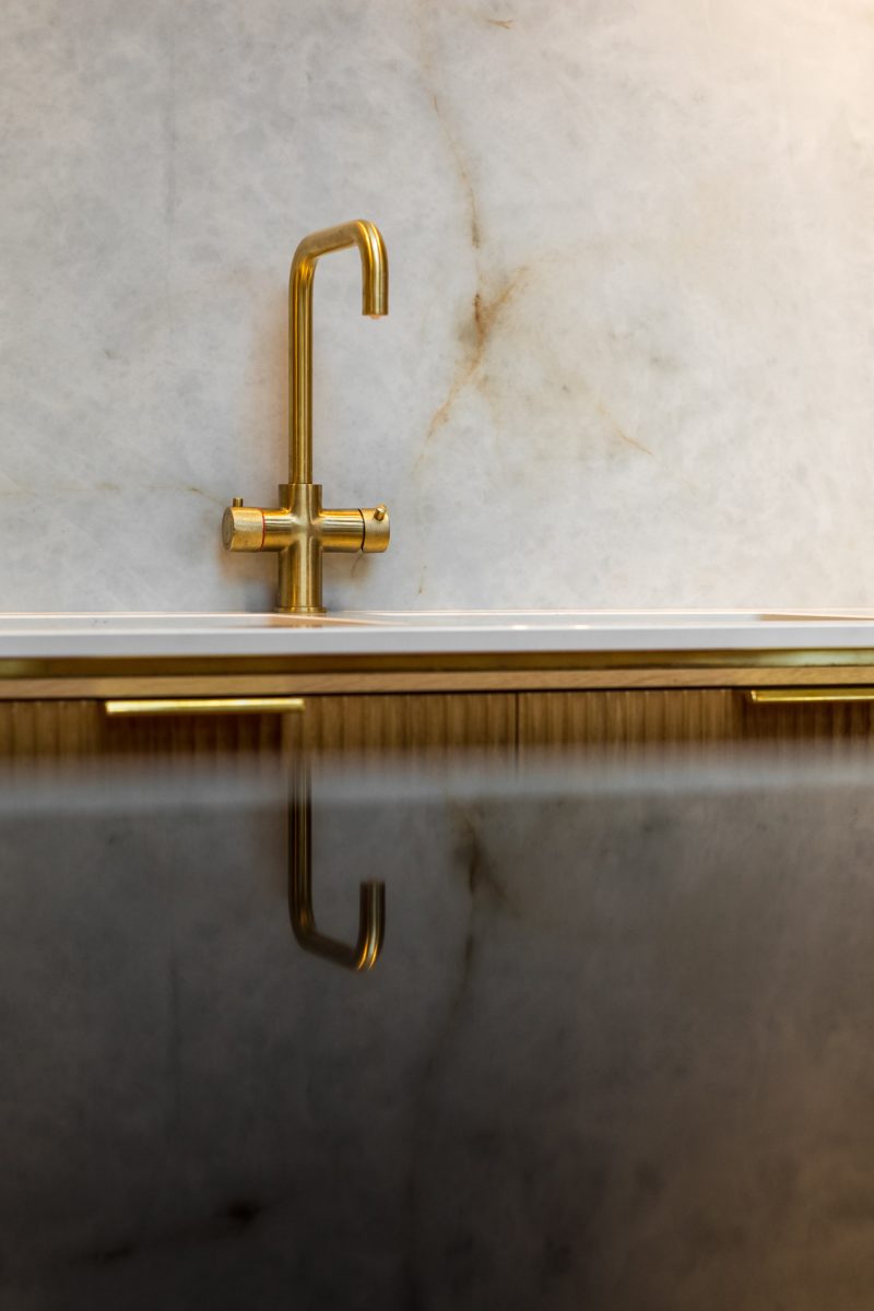 Close up of a golden tap with marble wall background